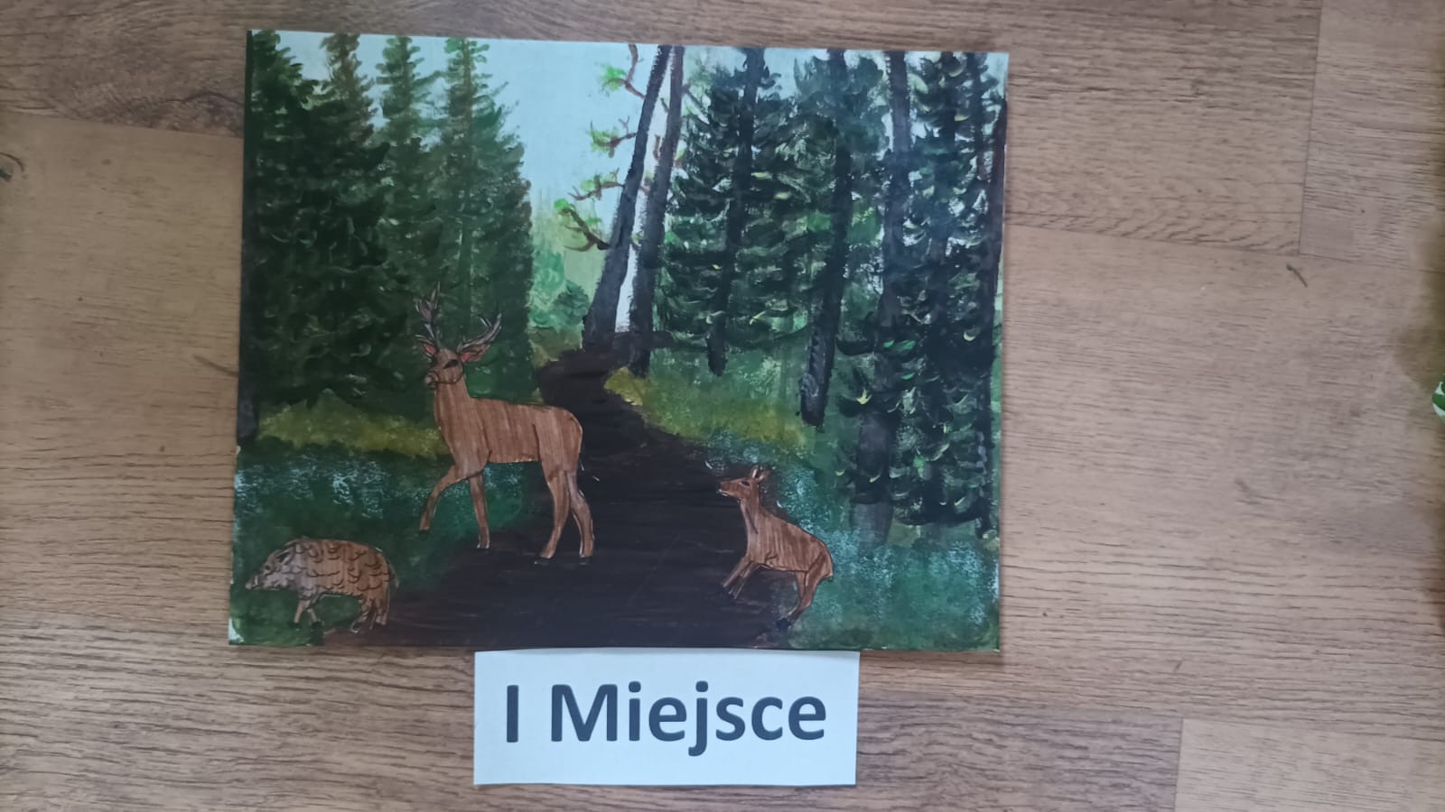 Pierwsze miejsce, obraz przedstawia jelenia, sarnę oraz dzika w lesie.