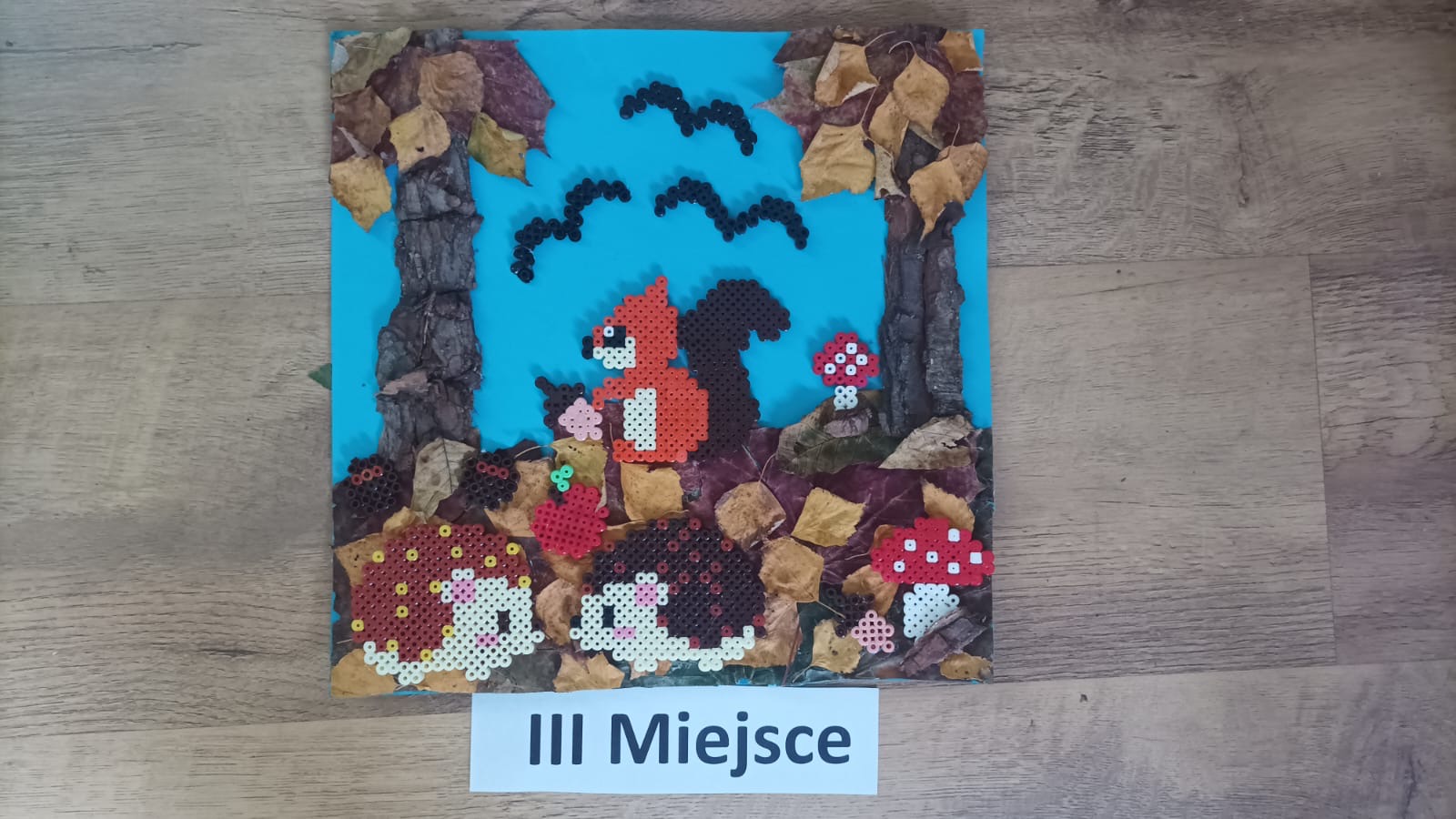 Trzecie miejsce, Wiewiórka oraz jeże zrobione ze zgrzanych koralików na tle środowiska leśnego.