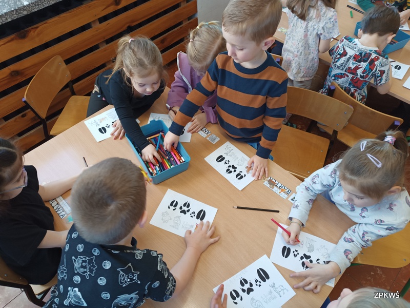 Dzieci siedzące przy stoliku zastanawiają się jak pokolorować zwierzęta