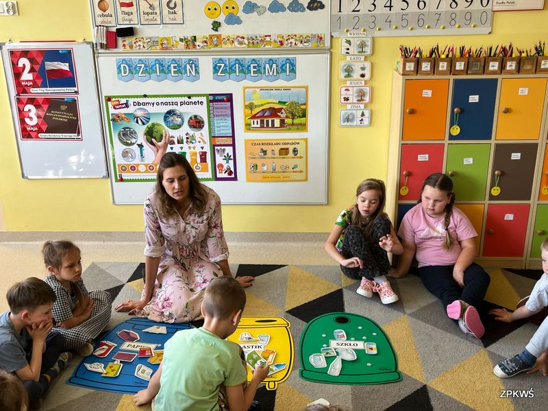 Grupa dzieci wraz z przedstawicielem parków krajobrazowych dyskutuje nad celem akcji z okazji Dnia Ziemi