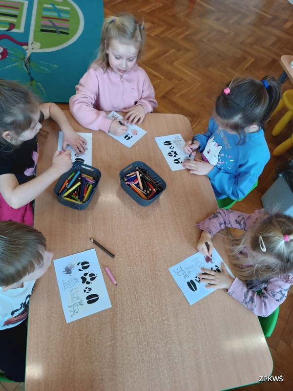 Dzieci przy stole kolorują kolorowanki 