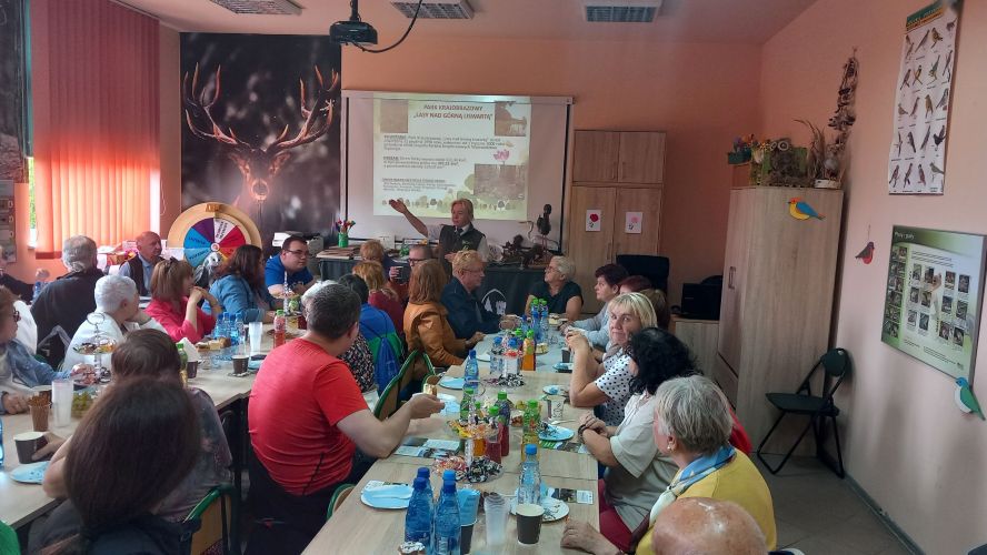 Pracownik ZPKWŚ opowiada o przyrodzie Parku Krajobrazowego Lasy nad Górną Liswartą w Sali edukacyjnej w Ośrodku w Kalinie. W tle prezentacja multimedialna z informacjami o Parku oraz zdjęciami.